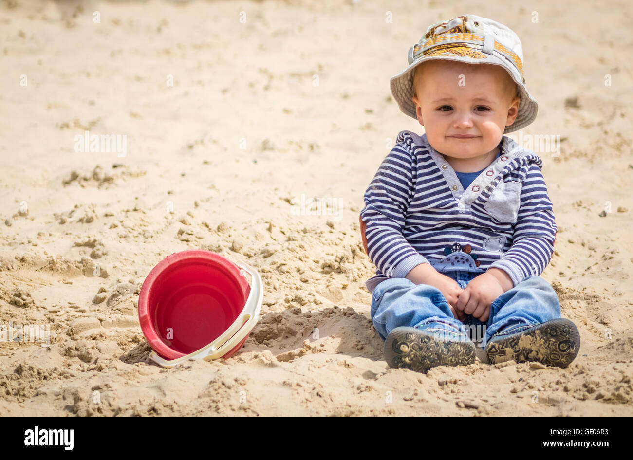 Adorable petit garçon assis dans un bac à sable dans une aire de jeux extérieure Banque D'Images