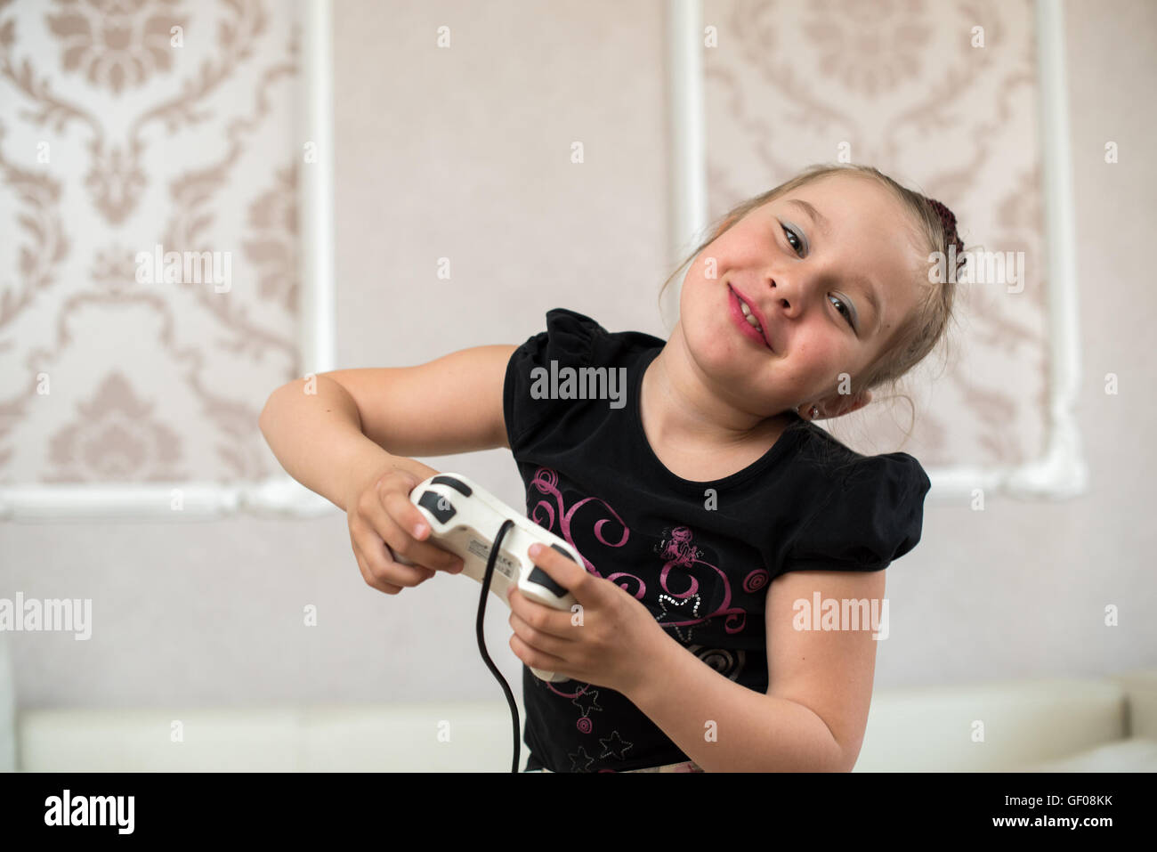 Jolie petite fille assise sur le canapé et jouer des jeux vidéo Banque D'Images