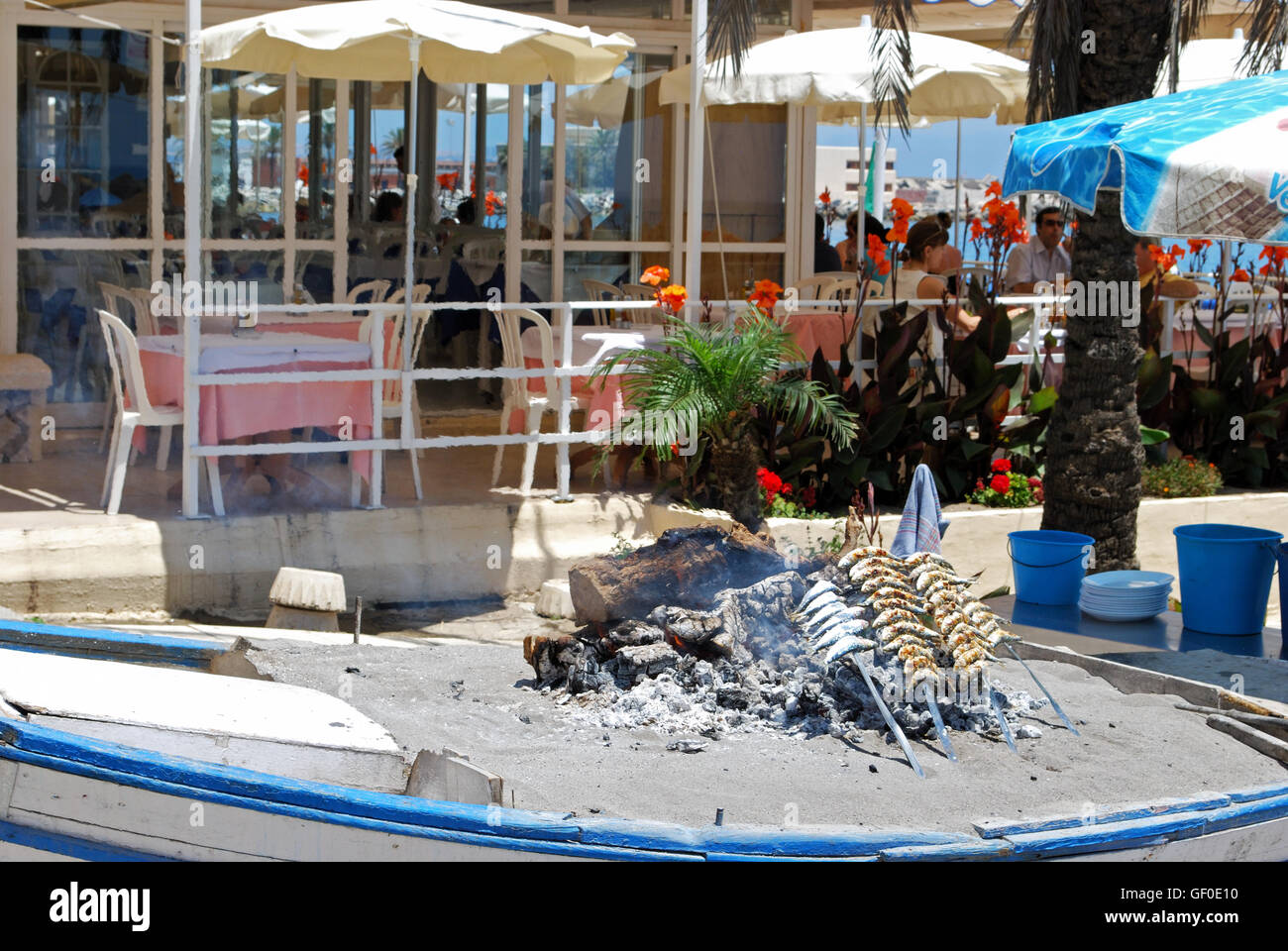 La cuisson des sardines dans un bateau rempli de sable à l'extérieur un chiringuito sur la plage, Fuengirola, province de Malaga, Andalousie, espagne. Banque D'Images