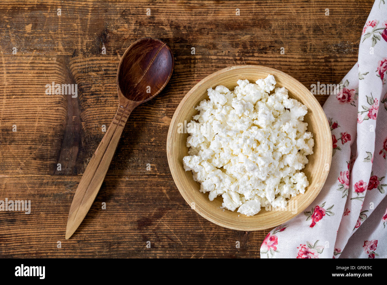 Les producteurs de fromage cottage (fromage) dans un bol en bois, cuillère en bois, textile sur table en bois rustique. Vue de dessus de la nourriture. La saine alimentation Banque D'Images