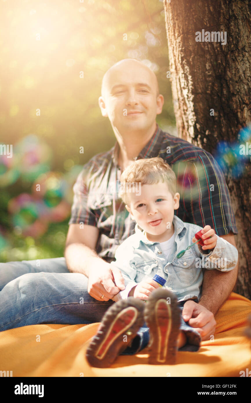 Père et son petit fils de passer du temps ensemble à l'extérieur. Selective focus sur des bulles de savon. Les effets de flou avec lumières bokeh. Banque D'Images