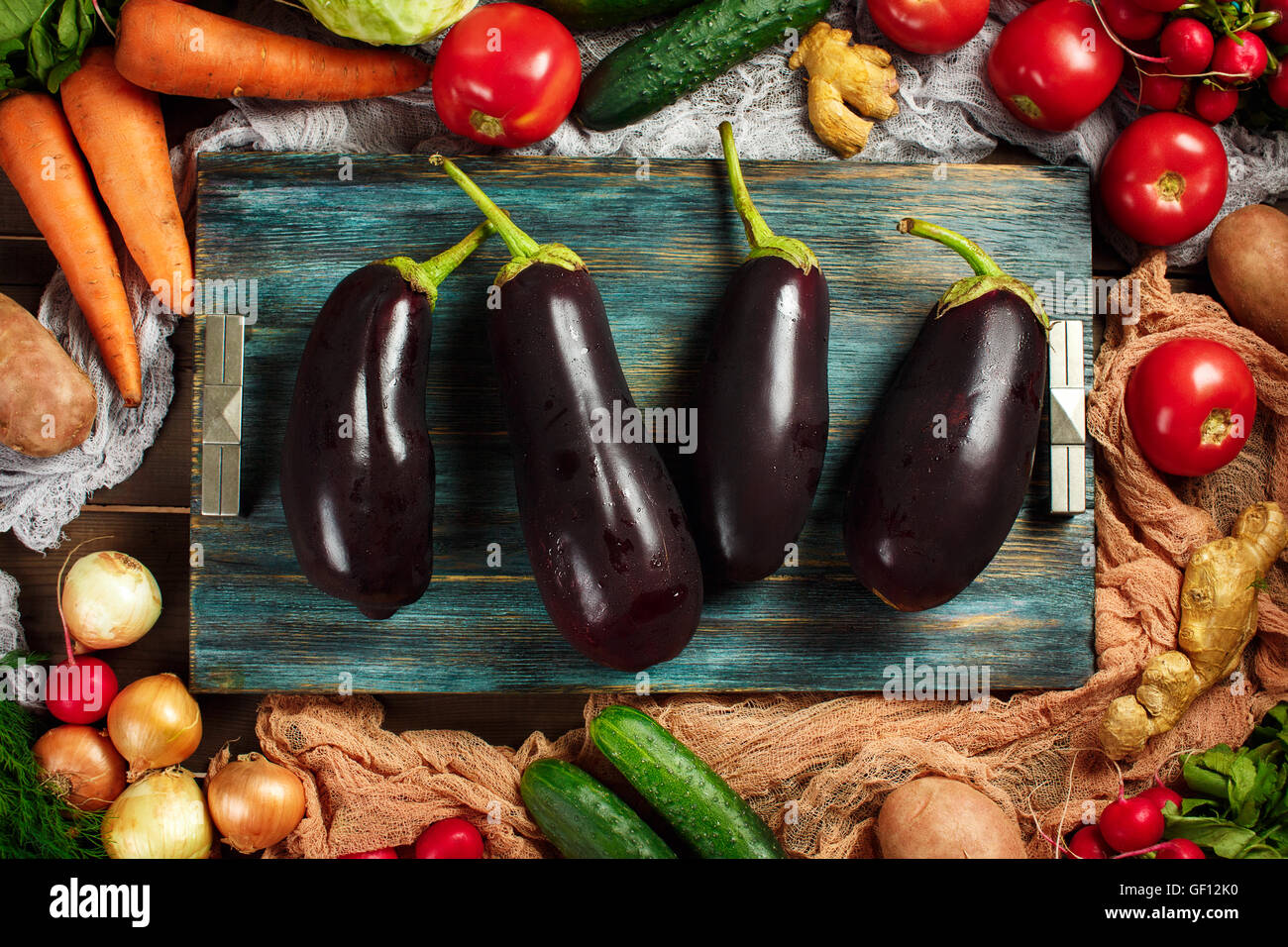 Grand frais aubergines close-up entre cadre fabriqué à partir de légumes mûrs sur fond de bois. Vue d'en haut. Les aubergines, le chou, les carottes. Banque D'Images