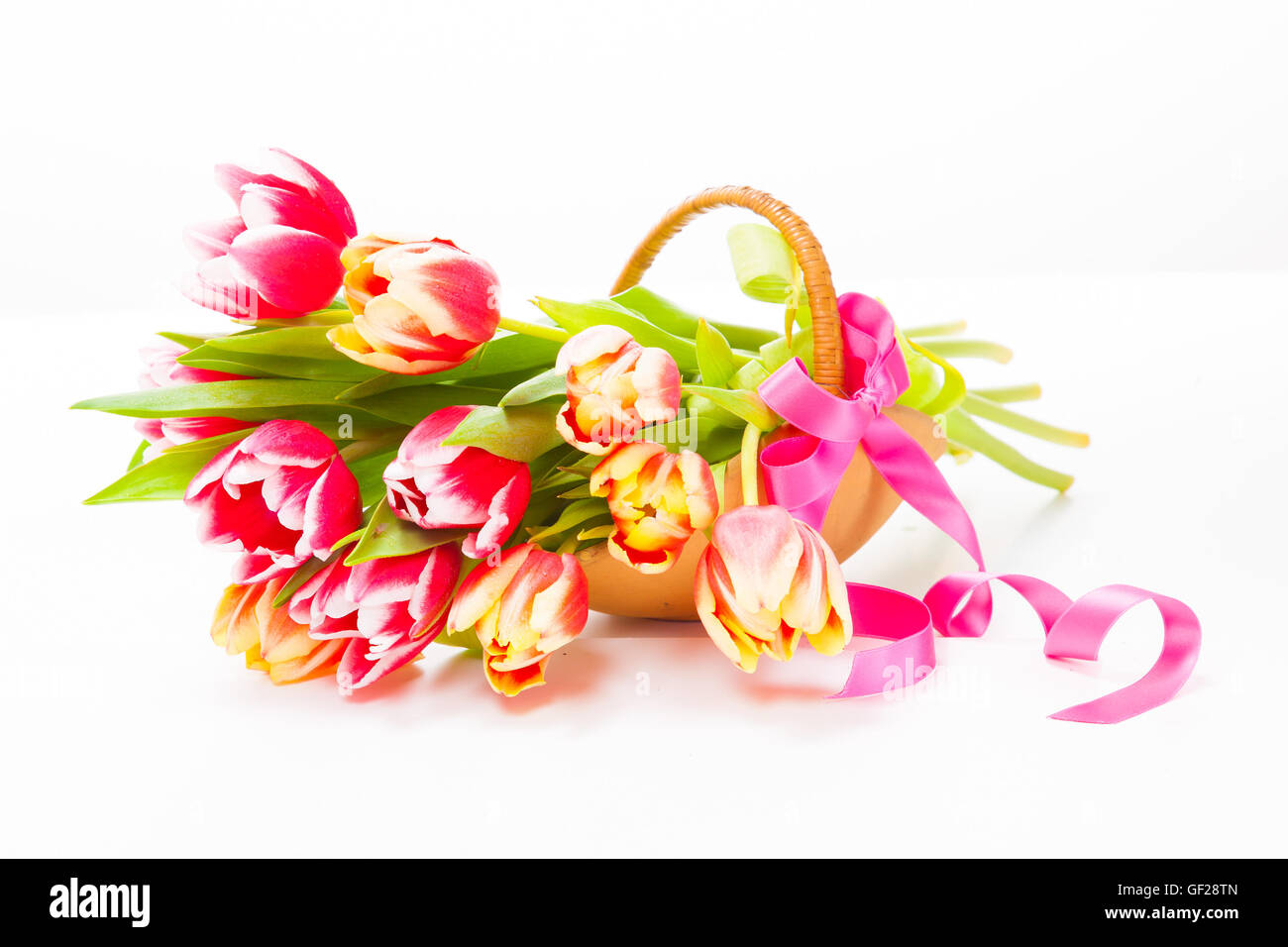 Panier avec des bouquets de tulipes colorées sur fond blanc Banque D'Images