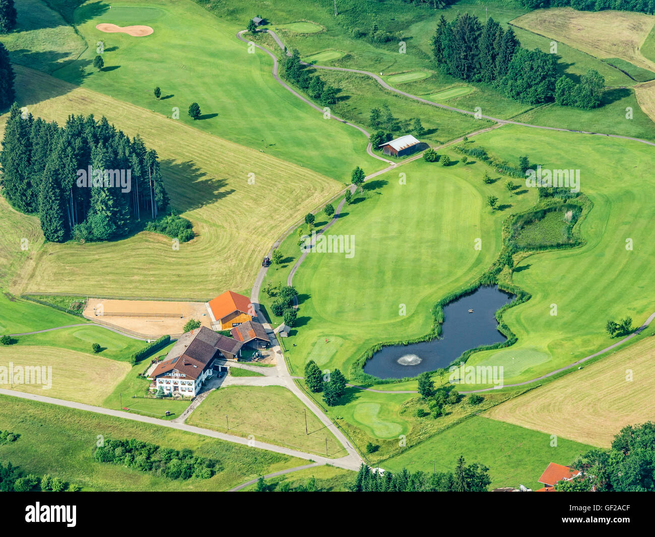 Maison de ferme isolée entourée de prairies, lac avec fontaine, petit parcours de golf, vue aérienne, la pente des alpes bavaroises près de Oberstd Banque D'Images