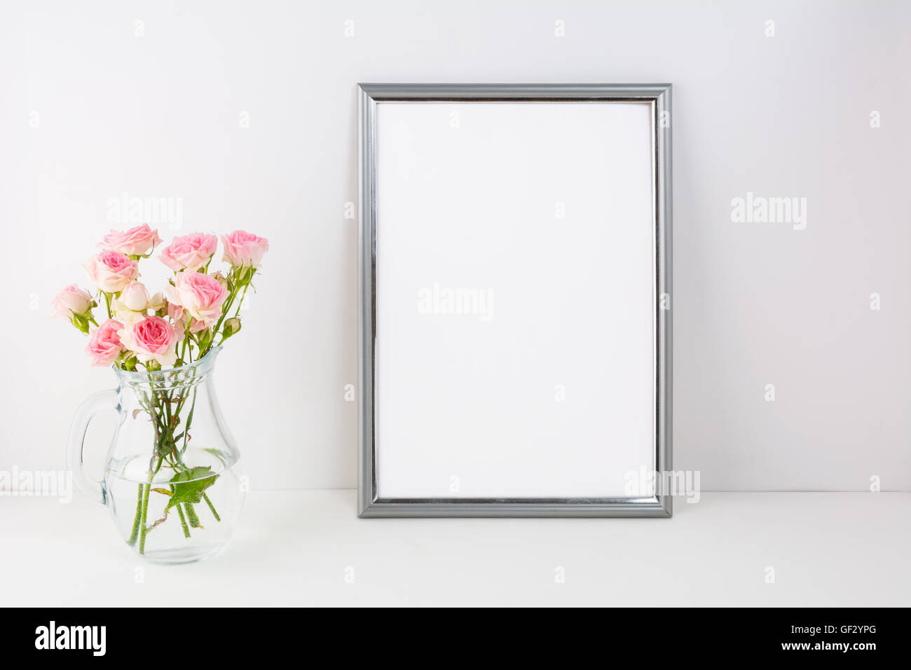Maquette du châssis d'argent avec roses roses. Portrait ou poster cadre blanc immersive. Cadre blanc vide immersive pour la présentation d'œuvres d'art. Banque D'Images
