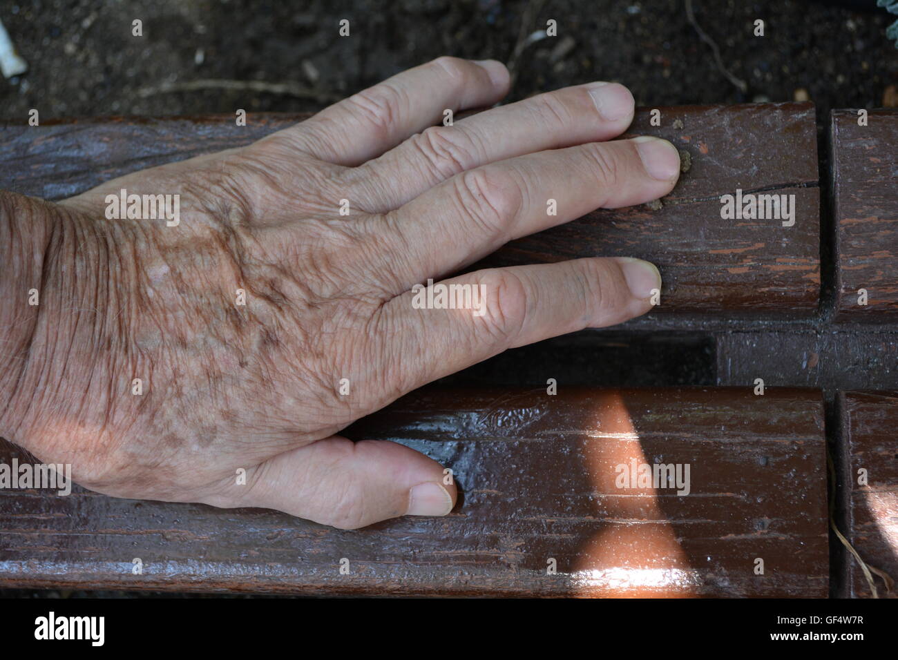 Man Main. Une main d'un vieil homme se reposant sur un banc. Banque D'Images