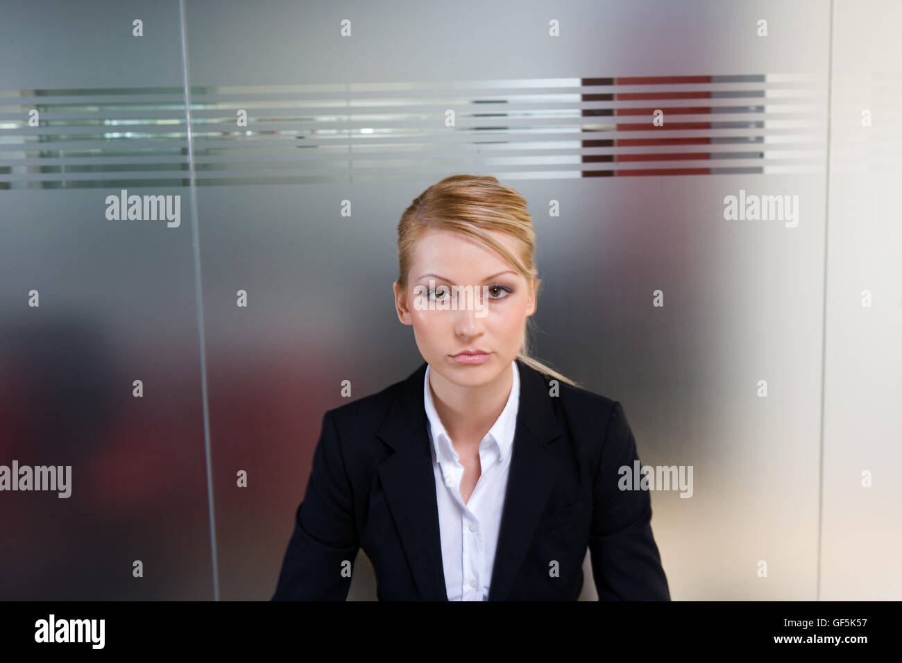 Profil d'une femme directrice assis en face d'un mur de verre. Banque D'Images