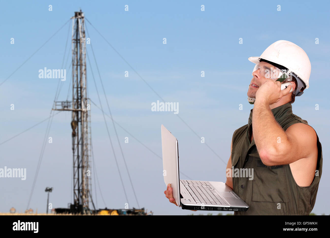 Travailleur de l'huile avec ordinateur portable et rig Banque D'Images