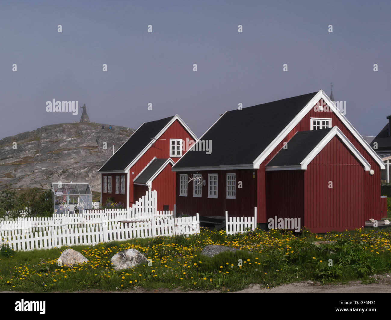 Maisons en bois peint rouge blanc avec jardins clôturés de piquetage avec les émissions de capitale du Groenland Nuuk vue de Hans Egede statue sur la colline en arrière-plan Banque D'Images