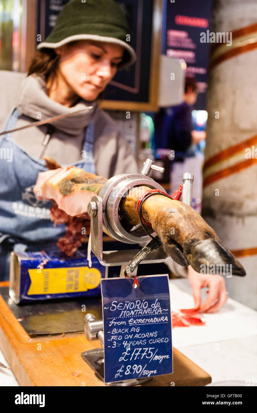 Borough Market, London. Un boucher découpe de fines tranches de viande à partir d'un joint de jambon. Banque D'Images