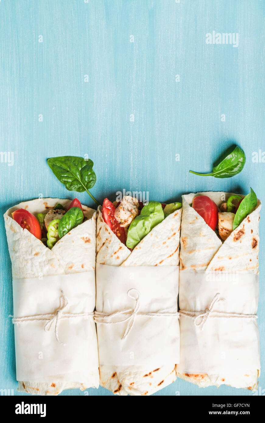 Snack lunch santé. Trois tortillas avec filet de poulet grillé et légumes frais sur fond de bois peint bleu turquoise Banque D'Images