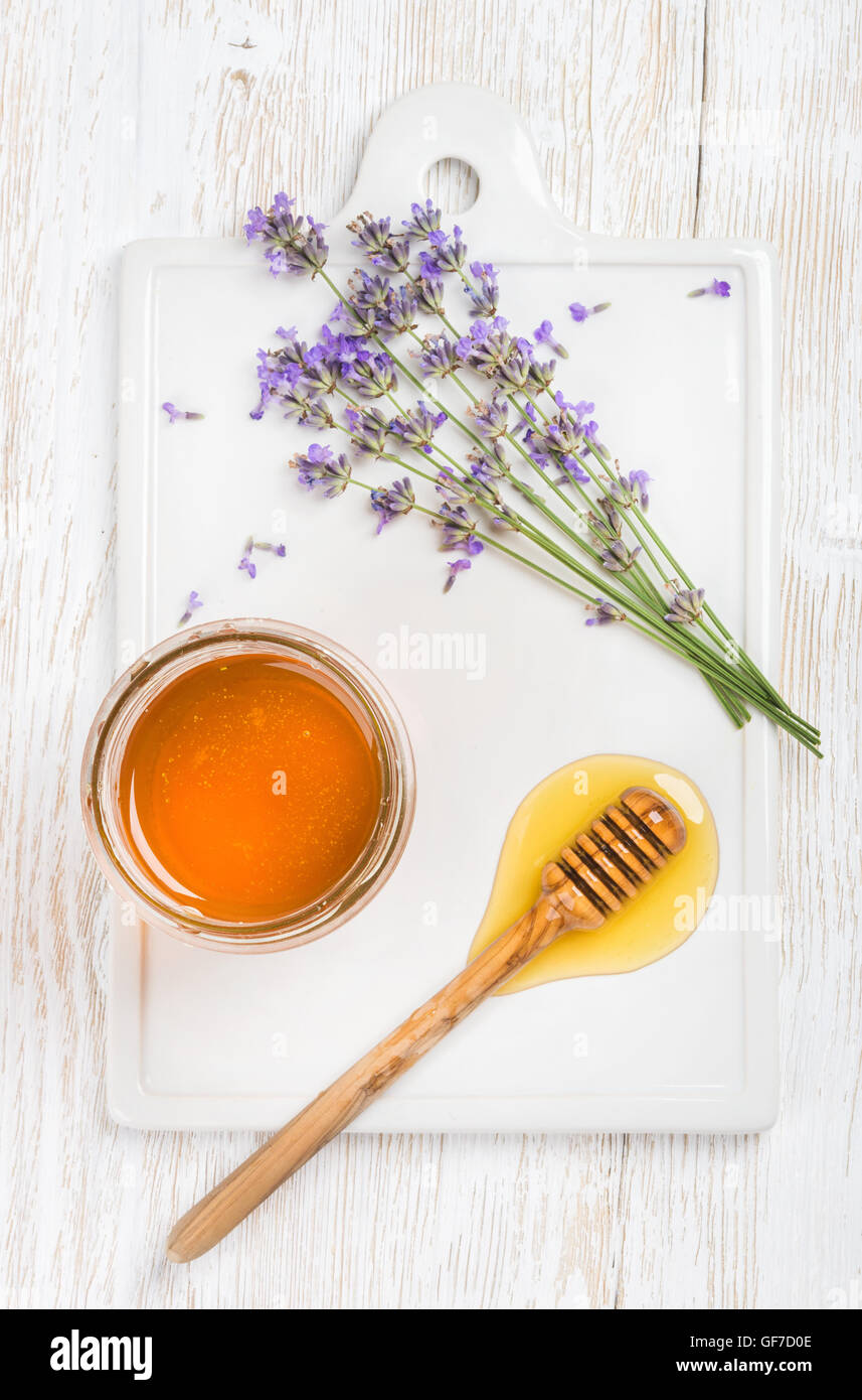 Le miel de lavande dans un bocal en verre avec des fleurs sur fond blanc Banque D'Images