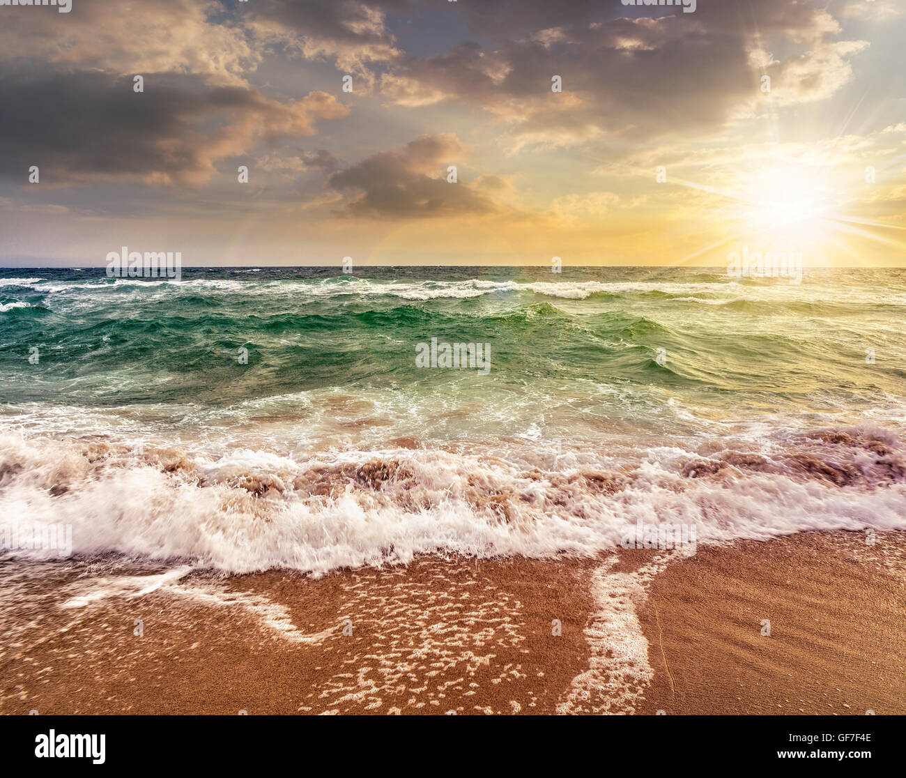 Vert et mer vague puissante attaque la plage de sable fin et pause sur eux dans la lumière du soir Banque D'Images
