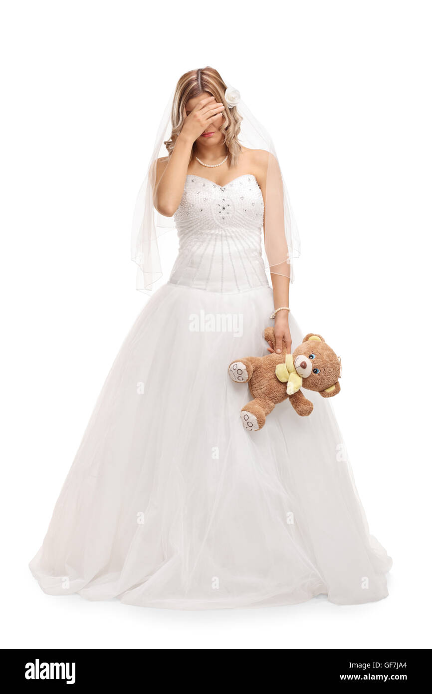 Verticale sur toute la longueur d'un coup triste young bride holding a teddy bear isolé sur fond blanc Banque D'Images