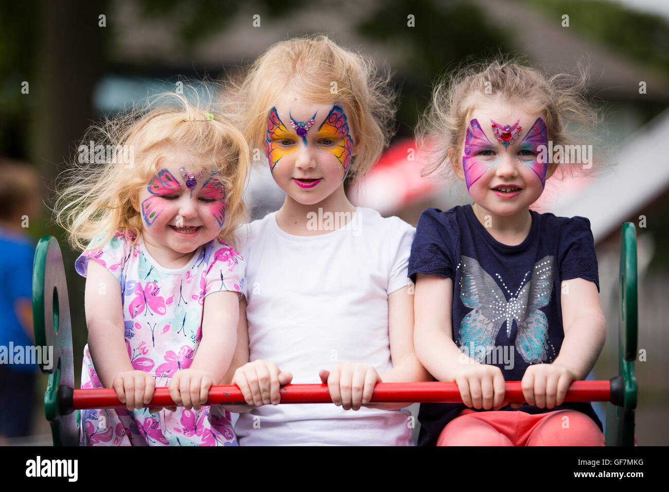 Enfants Les enfants Les enfants de 3 sœurs filles / fille avec un miroir de maquillage bijoux & visages peints par l'artiste professionnel à juste parti Banque D'Images