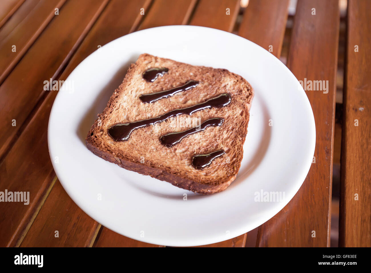 Chocolat à tartiner sur des toasts en disque blanc sur bois fenêtre table light Banque D'Images