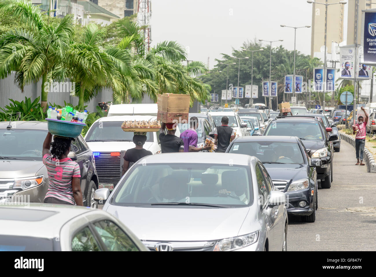 La sauvette plis leurs marchandises dans le trafic, Victoria Island, Lagos, Nigeria, Afrique de l'Ouest Banque D'Images