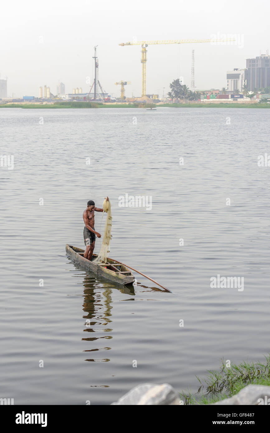 Pêcheur en canoë-kayak à deux côtes, pêche dans les eaux du Kuramo avec le contexte de développement de l'Atlantique Eko. Lagos, Nigéria, Afrique Banque D'Images