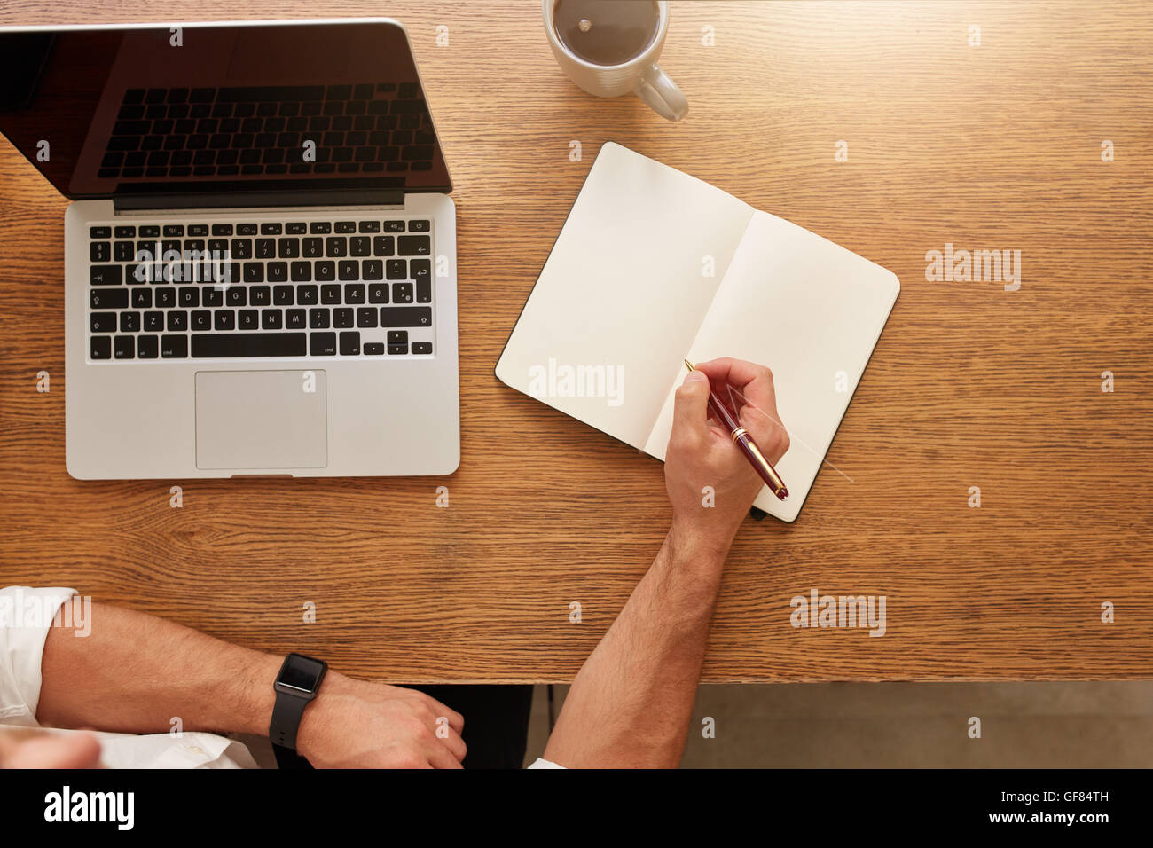 Close up of man notes in personal portable avec un ordinateur portable et tasse de café sur la table. Banque D'Images