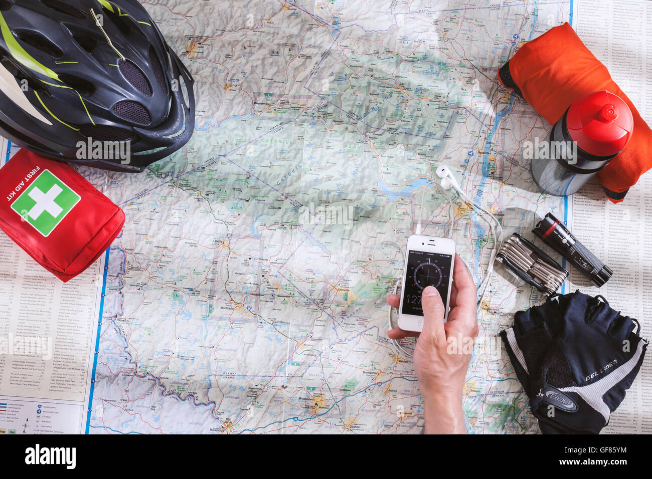 Accessoires Vélos répartis sur la carte lors de la planification d'une excursion à bicyclette dans les montagnes avec application boussole sur smartphone dans la main Banque D'Images