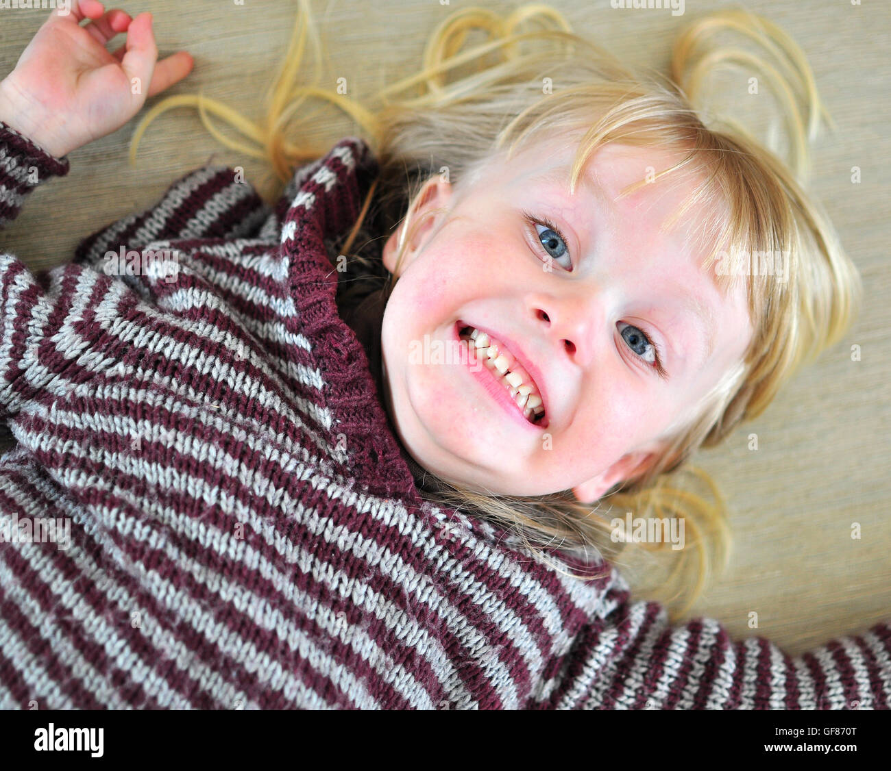 Cute smiling baby avec une longue chevelure blonde allongée sur le lit Banque D'Images