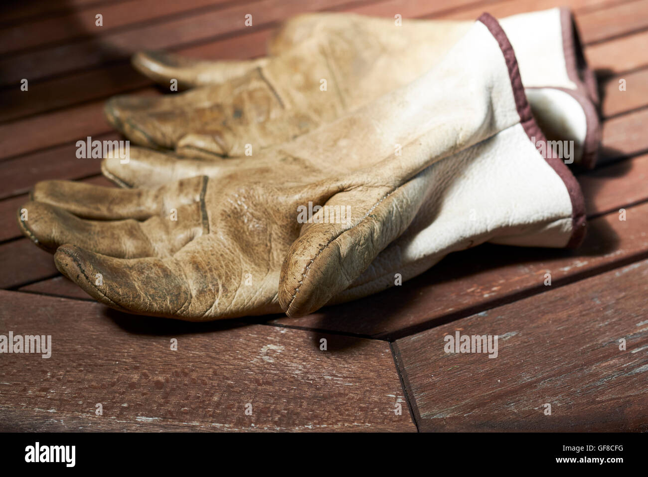 Porter des gants de travail en cuir sur une table d'extérieur en bois. Banque D'Images