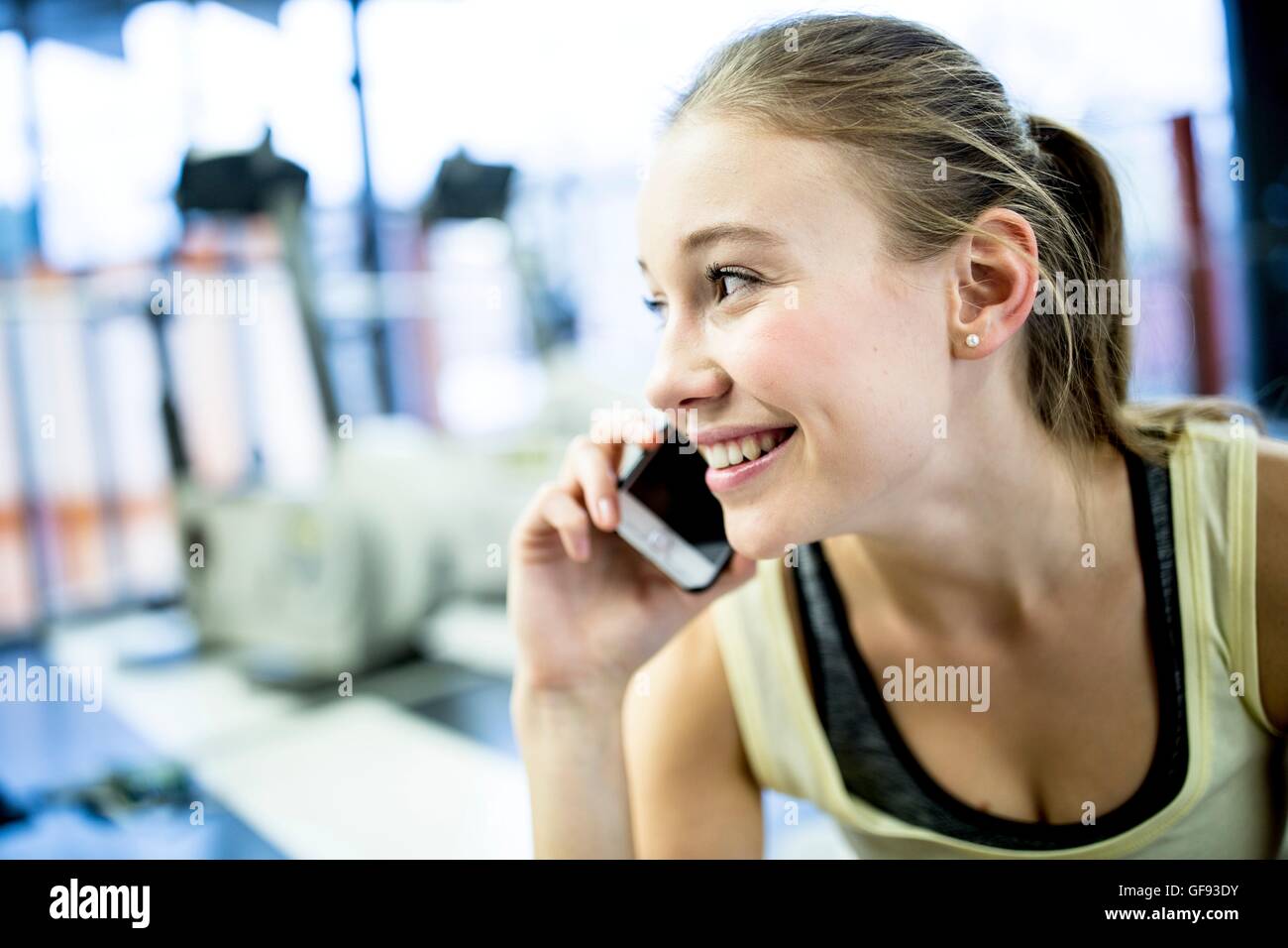 Parution de la propriété. Parution du modèle. Young woman smiling and talking on mobile phone dans la salle de sport. Banque D'Images