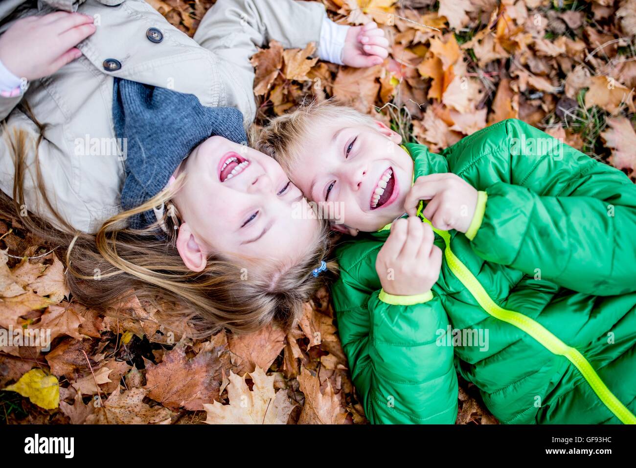 Parution du modèle. Les enfants se trouvant sur les feuilles séchées en automne et de rire. Banque D'Images