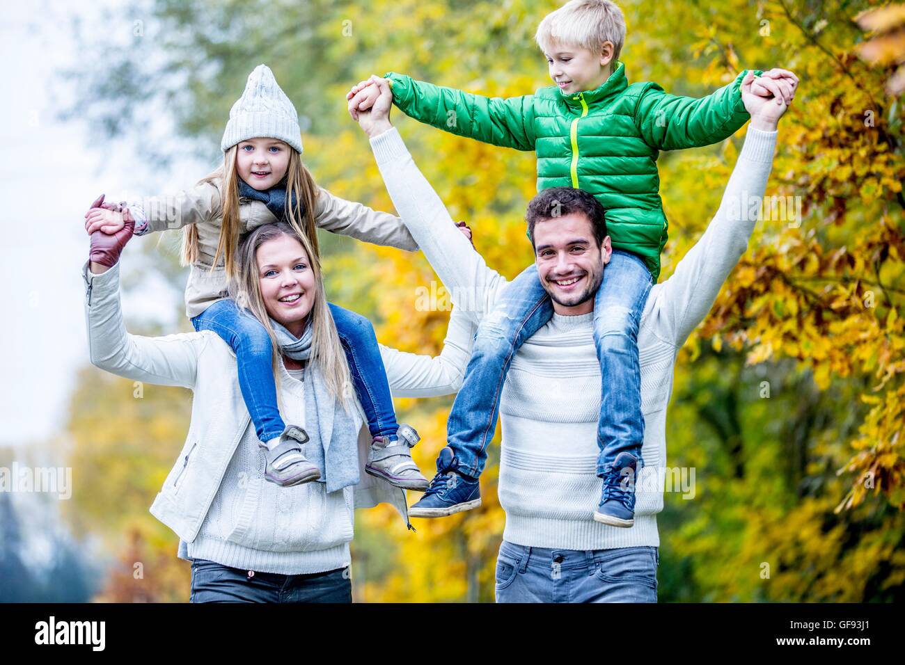 Parution du modèle. Les parents avec leurs enfants sur les épaules, à l'automne, en souriant. Banque D'Images