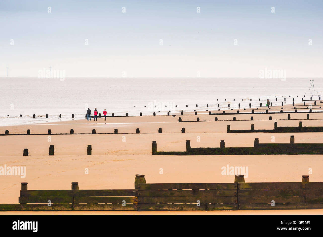 Côte d'Essex, vue sur un après-midi d'hiver d'une famille qui fait une promenade sur une plage déserte près de Frinton dans Essex, Angleterre, Royaume-Uni. Banque D'Images