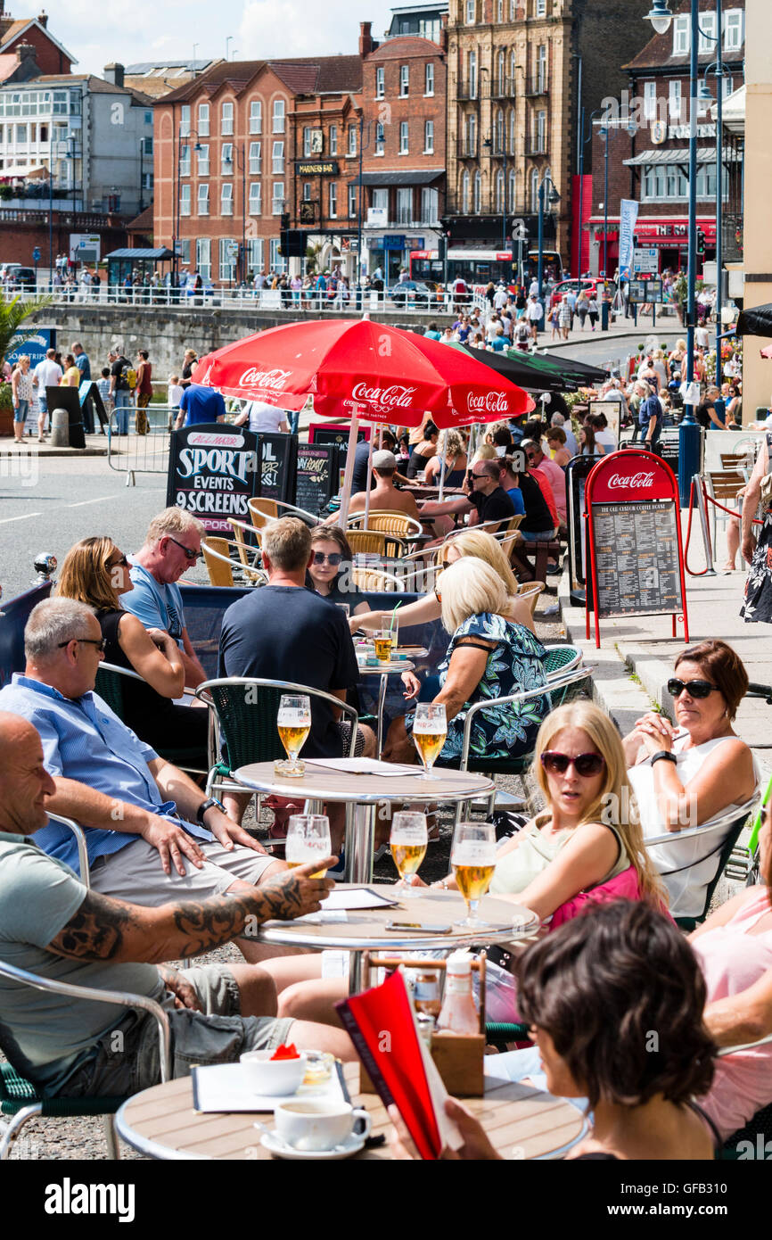 Front de l'Anglais à Ramsgate avec des gens assis à des tables et des  chaises à l'ombre des parasols, prendre un verre au cours de temps très  chaud en été Photo Stock -