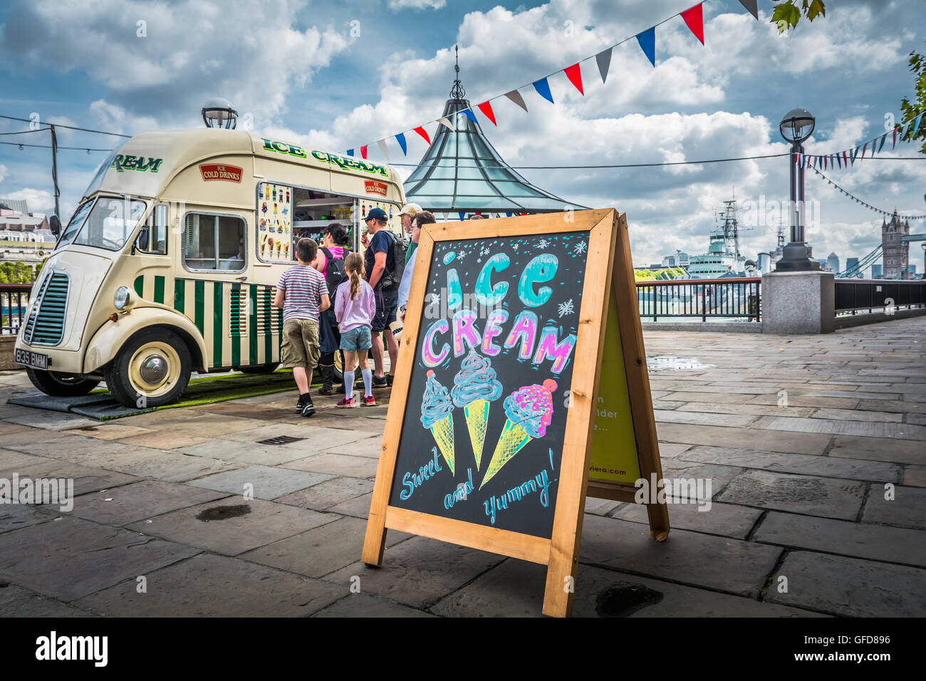 Familles faisant la queue devant un fourgon de crème glacée à côté de London Bridge City Pier sur la Tamise à Londres, Royaume-Uni Banque D'Images