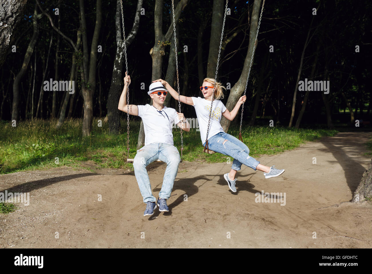 Cheerful couple sur la balançoire dans la forêt, l'heure d'été Banque D'Images