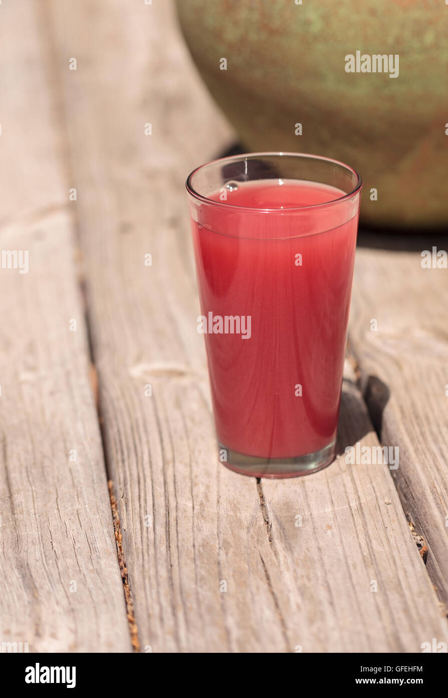 Verre de rose pastèque rouge verre de jus de fruits en été sur une table de pique-nique rustique. Banque D'Images