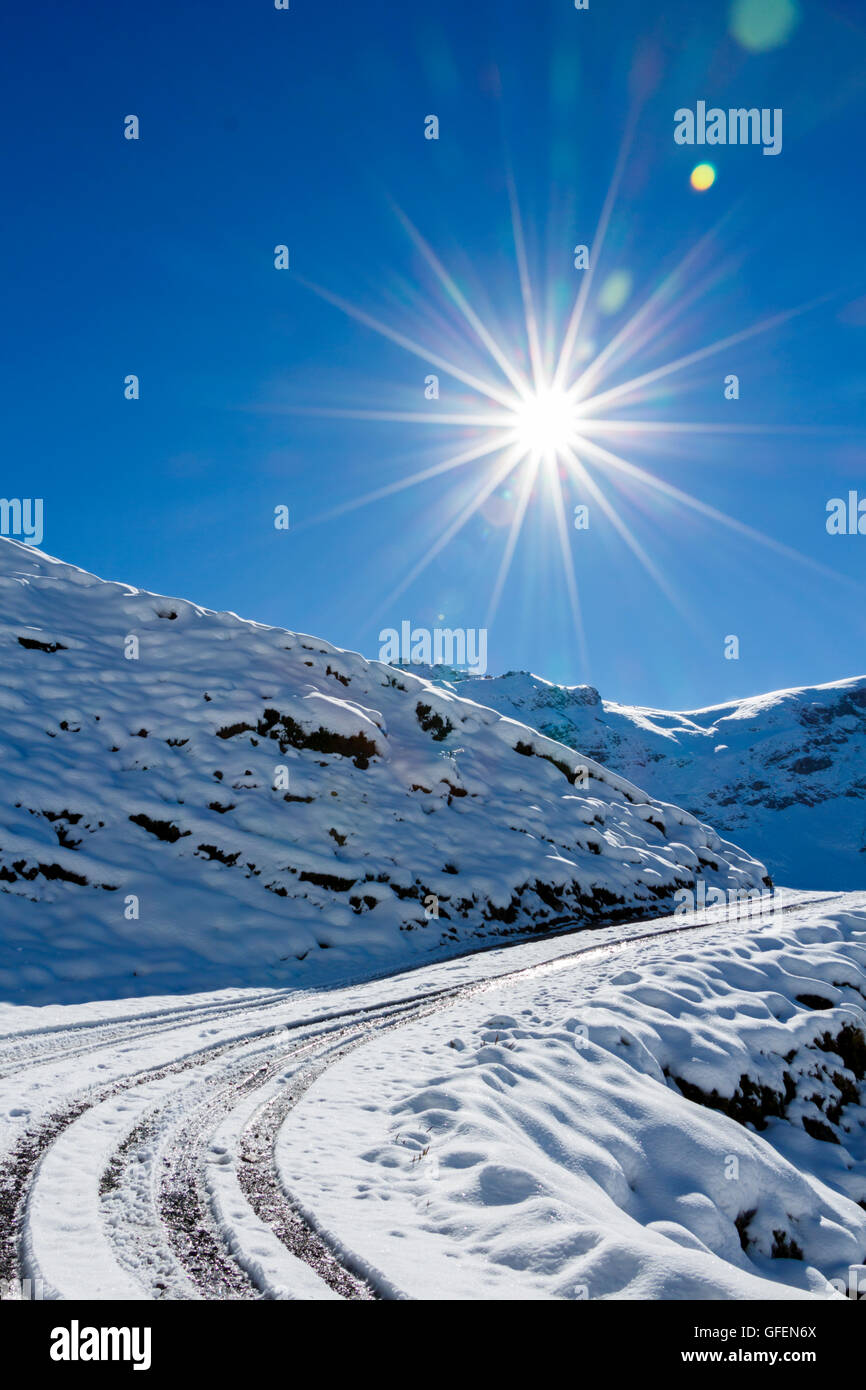 Route de montagne avec des traces de pneus et le soleil directement en avant Banque D'Images