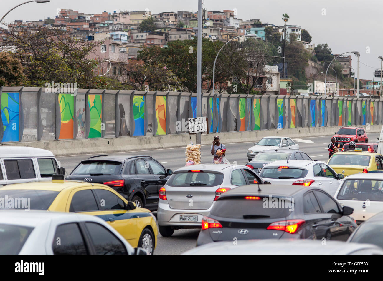 Habitants de Complexo da Mare, un immense réseau de favelas qui siège aux côtés de la Linha Vermelha ( ligne rouge ), la route principale de l'aéroport international de Rio de Janeiro au centre-ville, à travailler comme vendeurs de rue pendant les heures de pointe à l'expreessway - depuis 2010, la communauté a été clôturé à partir de l'autoroute par d'immenses panneaux Perspex - les autorités affirment qu'ils fournissent une barrière acoustique, les sections locales le décrivent comme un "mur de la honte", une autre façon de cacher les pauvres. Banque D'Images