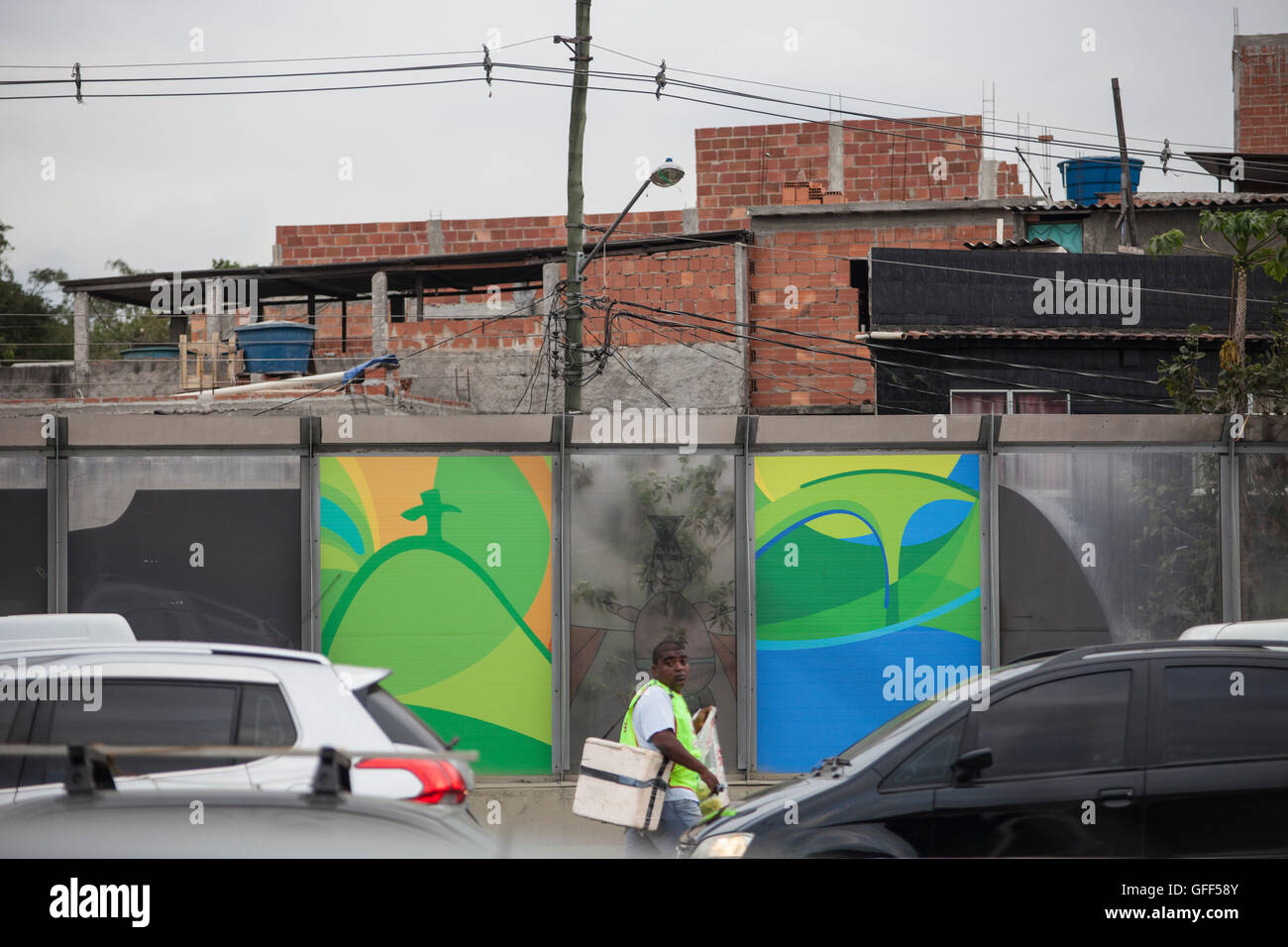 Habitants de Complexo da Mare, un immense réseau de favelas qui siège aux côtés de la Linha Vermelha ( ligne rouge ), la route principale de l'aéroport international de Rio de Janeiro au centre-ville, à travailler comme vendeurs de rue pendant les heures de pointe à l'expreessway - depuis 2010, la communauté a été clôturé à partir de l'autoroute par d'immenses panneaux Perspex - les autorités affirment qu'ils fournissent une barrière acoustique, les sections locales le décrivent comme un "mur de la honte", une autre façon de cacher les pauvres. Juste avant les Jeux Olympiques, la ville a commencé à plâtrer l 3 m de haut, 7 km de panneaux avec des affiches olympiques s Banque D'Images