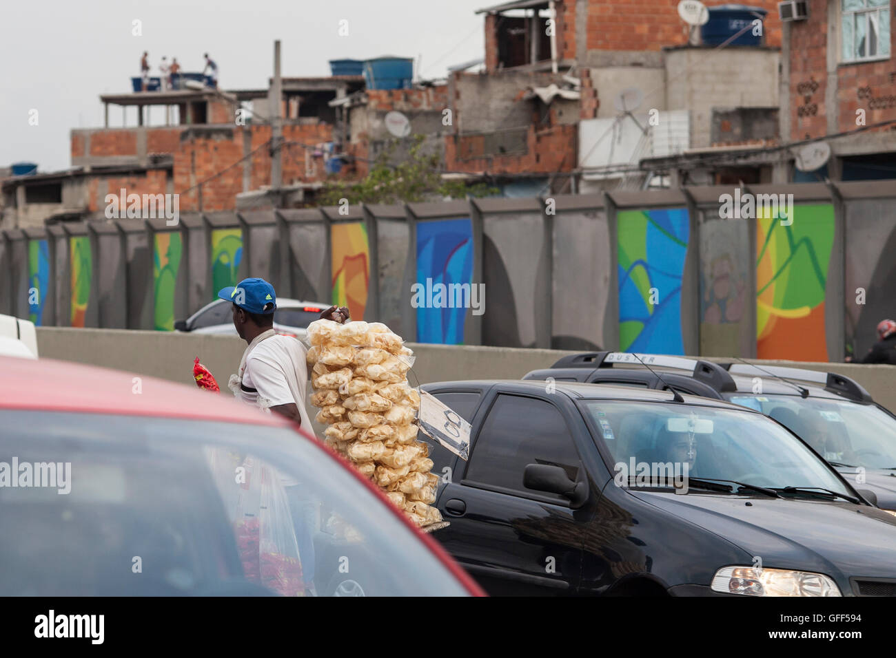 Habitants de Complexo da Mare, un immense réseau de favelas qui siège aux côtés de la Linha Vermelha ( ligne rouge ), la route principale de l'aéroport international de Rio de Janeiro au centre-ville, à travailler comme vendeurs de rue pendant les heures de pointe à l'expreessway - depuis 2010, la communauté a été clôturé à partir de l'autoroute par d'immenses panneaux Perspex - les autorités affirment qu'ils fournissent une barrière acoustique, les sections locales le décrivent comme un "mur de la honte", une autre façon de cacher les pauvres. Banque D'Images