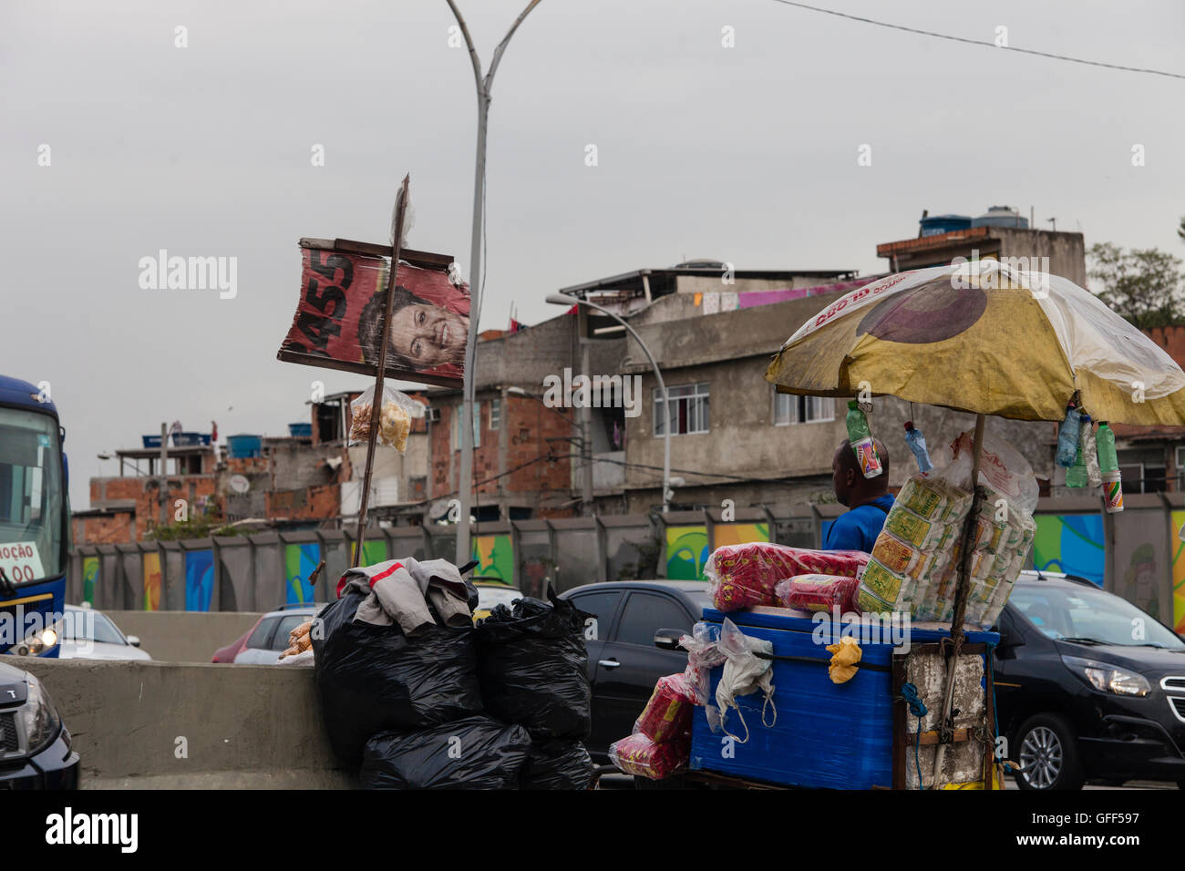 Habitants de Complexo da Mare, un immense réseau de favelas qui siège aux côtés de la Linha Vermelha ( ligne rouge ), la route principale de l'aéroport international de Rio de Janeiro au centre-ville, à travailler comme vendeurs de rue pendant les heures de pointe à l'expreessway - depuis 2010, la communauté a été clôturé à partir de l'autoroute par d'immenses panneaux Perspex - les autorités affirment qu'ils fournissent une barrière acoustique, les sections locales le décrivent comme un "mur de la honte", une autre façon de cacher les pauvres. Banque D'Images