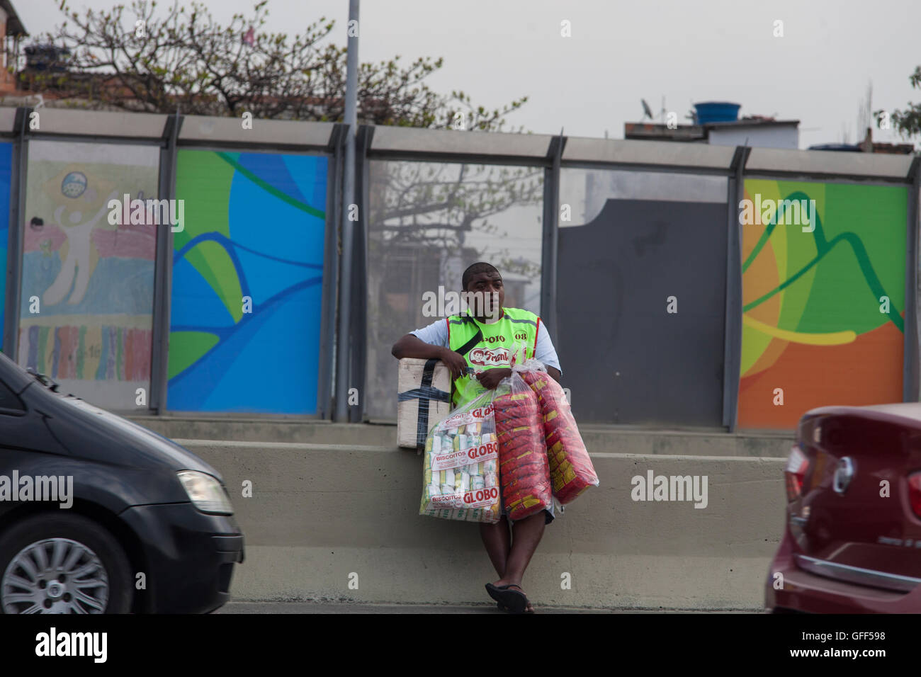 Habitants de Complexo da Mare, un immense réseau de favelas qui siège aux côtés de la Linha Vermelha ( ligne rouge ), la route principale de l'aéroport international de Rio de Janeiro au centre-ville, à travailler comme vendeurs de rue pendant les heures de pointe à l'expreessway - depuis 2010, la communauté a été clôturé à partir de l'autoroute par d'immenses panneaux Perspex - les autorités affirment qu'ils fournissent une barrière acoustique, les sections locales le décrivent comme un "mur de la honte", une autre façon de cacher les pauvres. Banque D'Images
