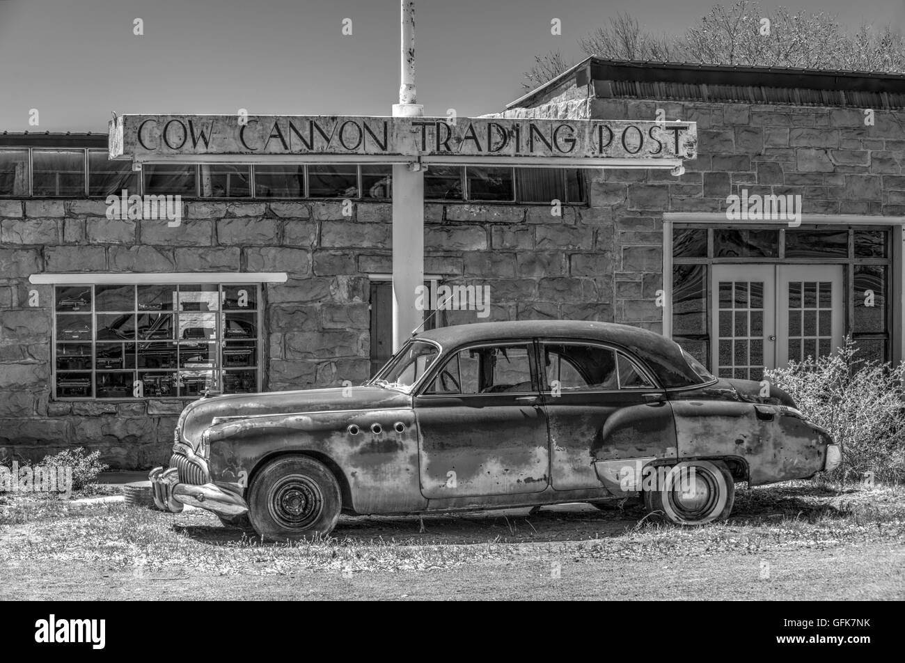 Un traitement monochrome artistique d'une vieille voiture en face d'un ancien poste de traite dans le désert américain Banque D'Images