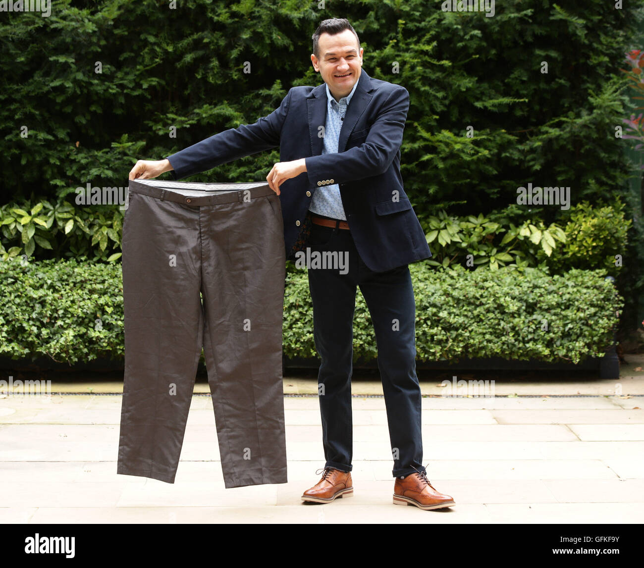 Danny Crosby, lauréat du prix Slimming World's Man of the Year 2016, pose pour des photos avec une paire de vieux pantalons qu'il portait avant de perdre huit pierres, lors d'un photocall à l'hôtel Ritz de Londres. Banque D'Images