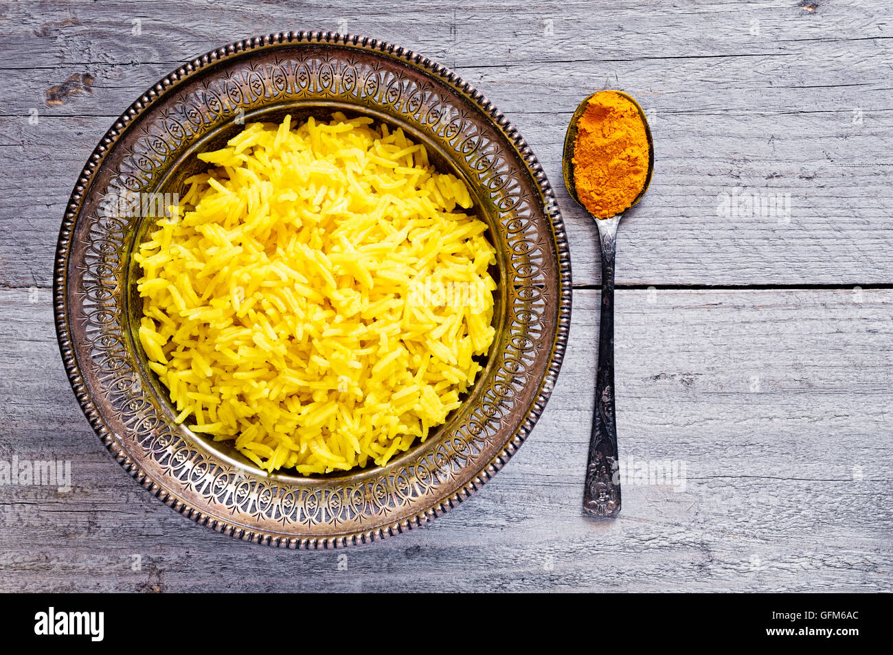 Vue de dessus d'un bol en métal antique avec curcuma cuit le riz au jasmin et vintage metal cuillère à café avec de la poudre de curcuma Banque D'Images