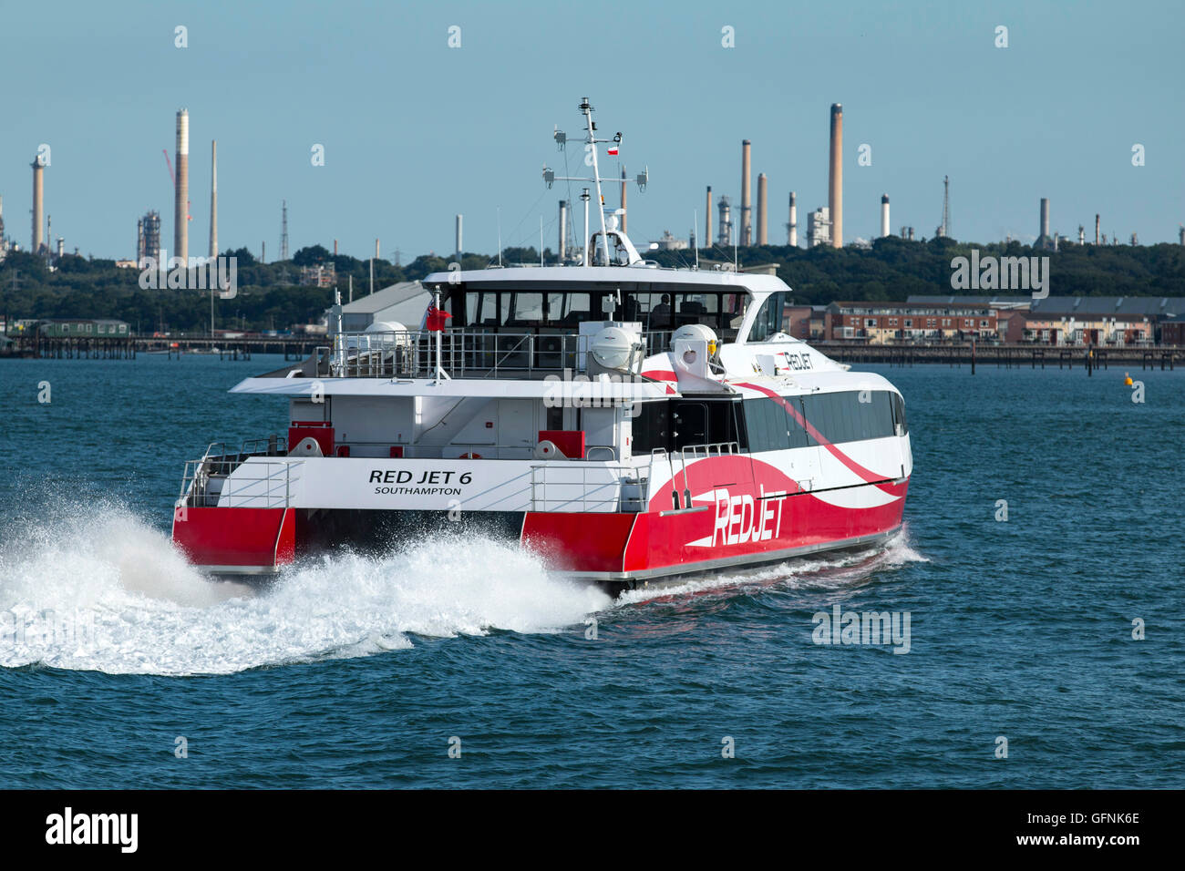 Fast ferry Red Funnel Jet rouge 6 de quitter la ville, Quai Southampton en route vers Cowes, île de Wight. La raffinerie de pétrole de Fawley est dans l'arrière-plan Banque D'Images