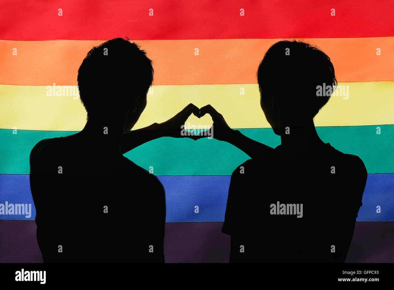 Homme couple silhouette contre le drapeau arc-en-ciel Banque D'Images