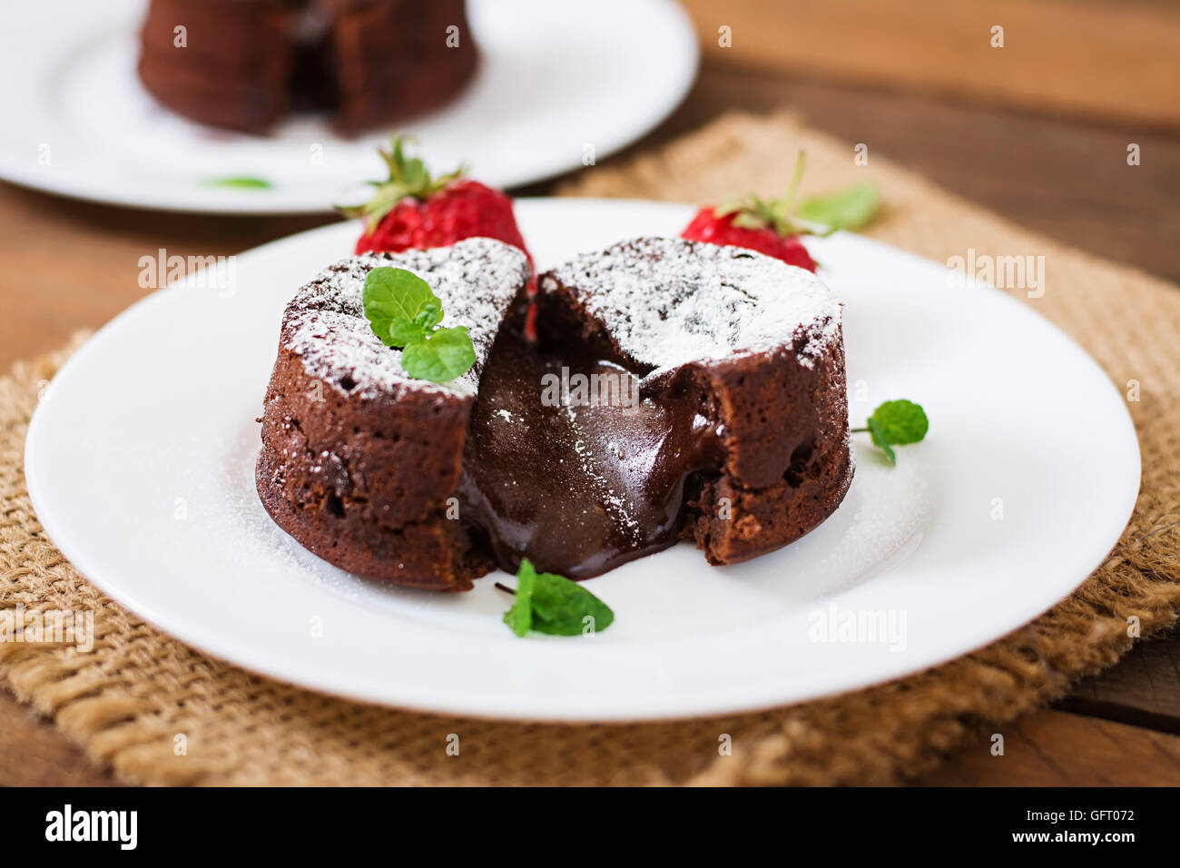 Fondant au chocolat (Cupcake) avec des fraises et du sucre en poudre Banque D'Images