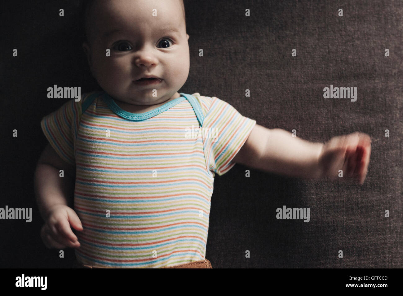 Une petite fille de six mois sur un stripey vest couchée sur le dos Banque D'Images