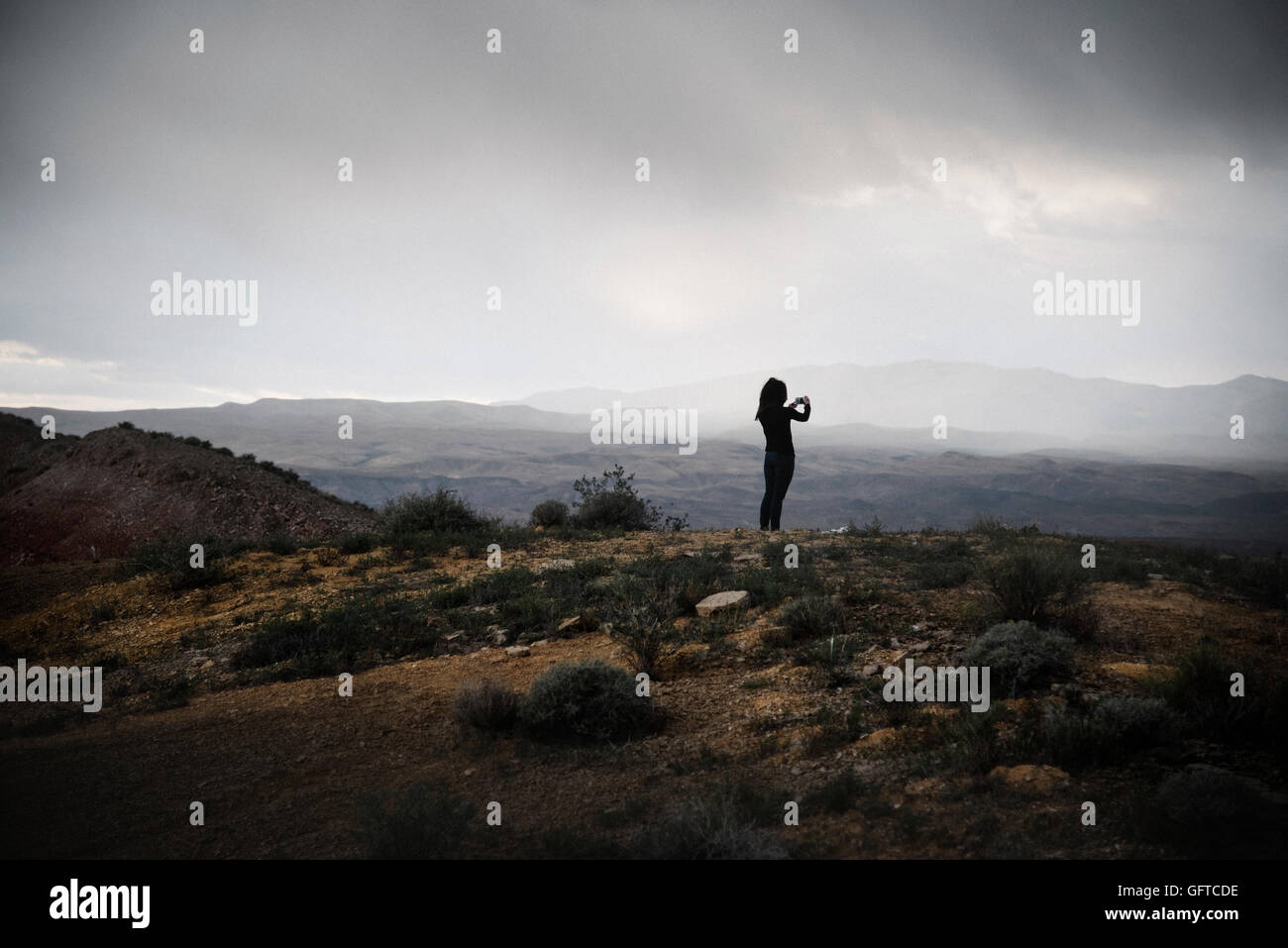Femme debout dans une prairie sous un ciel nuageux. Banque D'Images