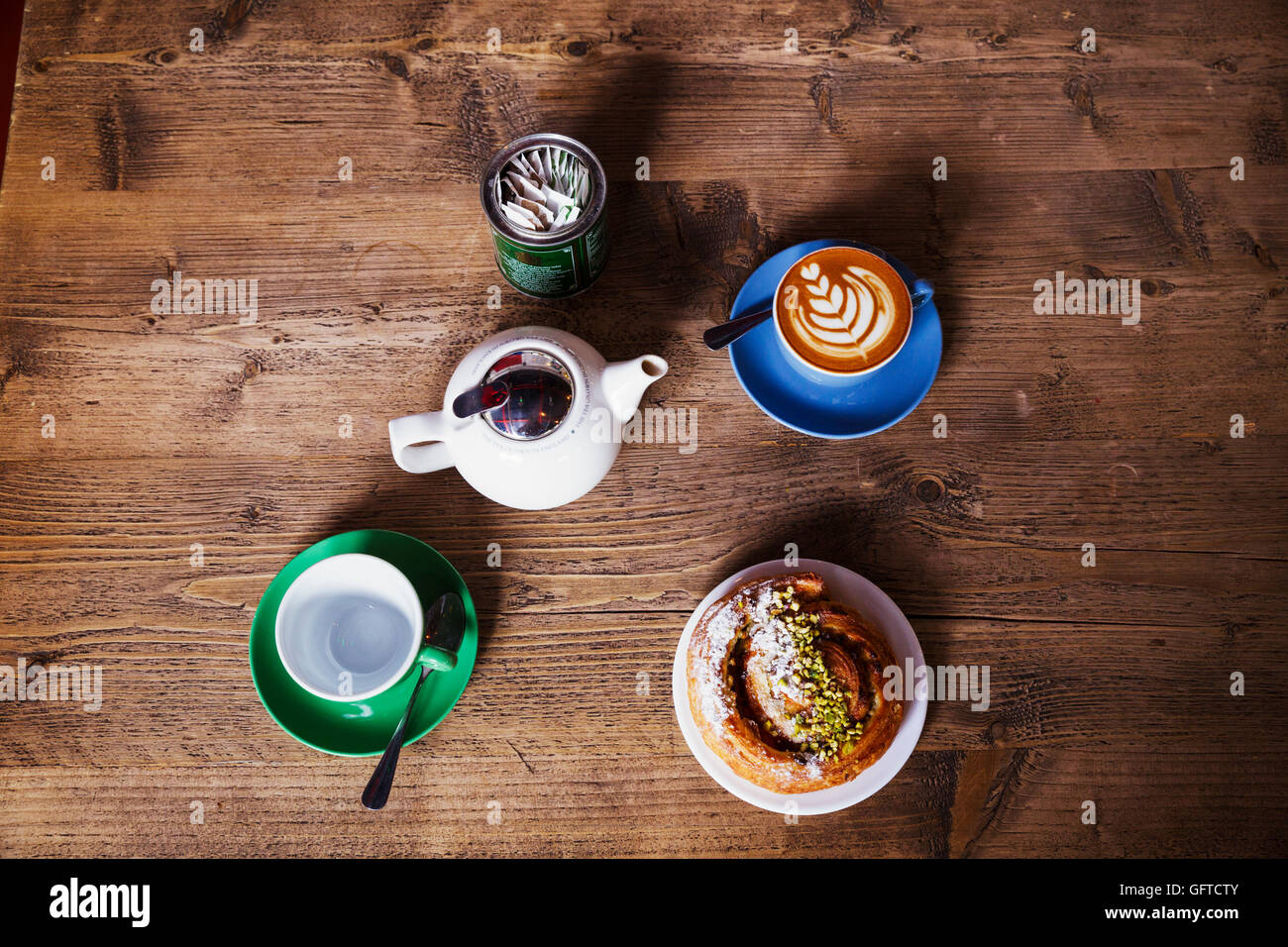 Vue d'un dessus de table avec une tasse de café une théière et tasse de thé et une pâtisserie sur une plaque Banque D'Images