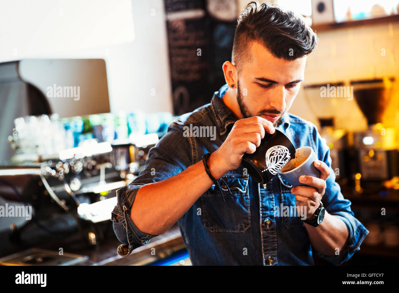 Un homme la préparation du cappuccino créer des modèles en mousse une tasse de café Banque D'Images